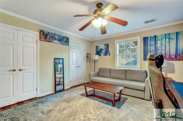 living area featuring visible vents, crown molding, a textured ceiling, and wood finished floors