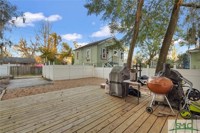 wooden deck with a fenced backyard and a grill