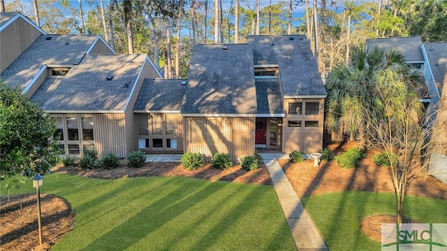 back of house with roof with shingles and a yard