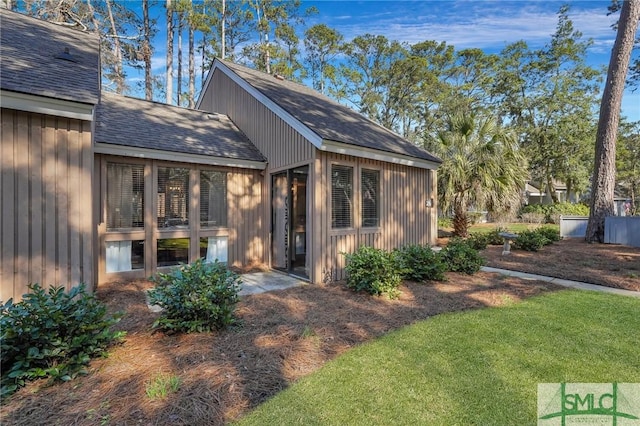 rear view of house featuring a shingled roof and a lawn