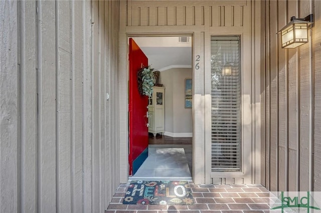 view of exterior entry with board and batten siding and visible vents