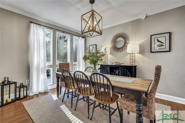 dining area featuring a notable chandelier, baseboards, and wood finished floors