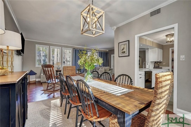 dining area with crown molding, a notable chandelier, visible vents, wood finished floors, and baseboards