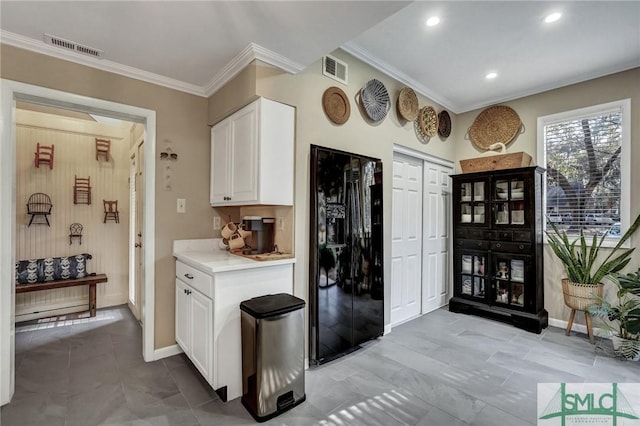 kitchen featuring visible vents, white cabinets, crown molding, and black fridge with ice dispenser