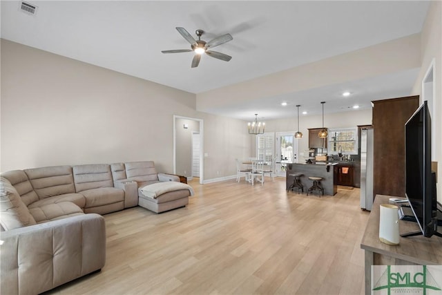 living room featuring recessed lighting, visible vents, light wood-style floors, baseboards, and ceiling fan with notable chandelier