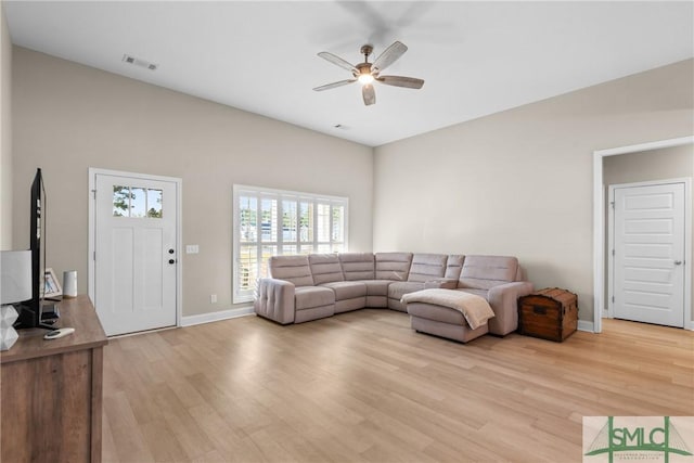 living area featuring a ceiling fan, baseboards, visible vents, and light wood finished floors