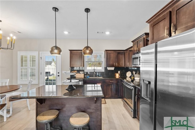 kitchen with visible vents, decorative backsplash, light wood-style flooring, stainless steel appliances, and a sink