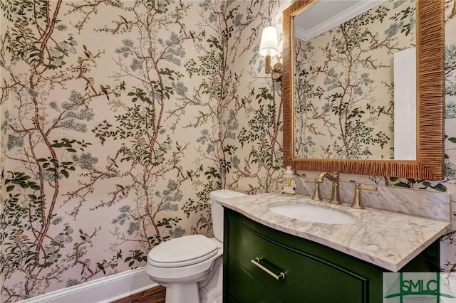 half bath with toilet, vanity, and wallpapered walls