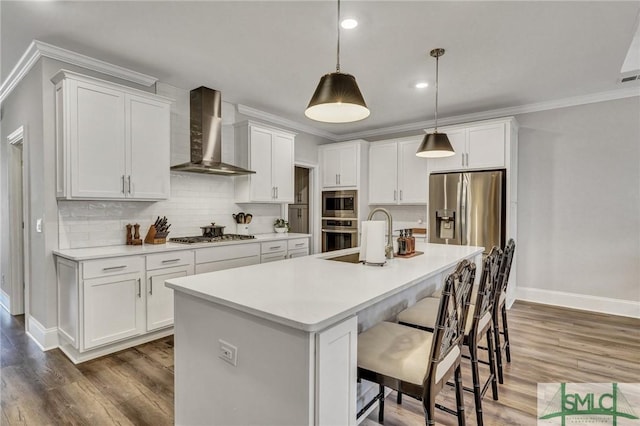 kitchen featuring crown molding, tasteful backsplash, appliances with stainless steel finishes, wood finished floors, and wall chimney exhaust hood