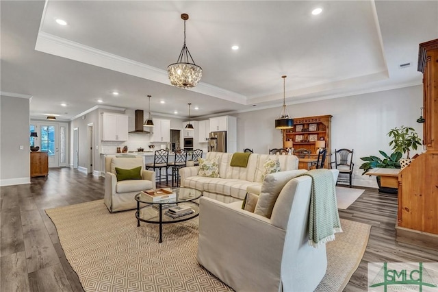 living area featuring ornamental molding, a tray ceiling, wood finished floors, and baseboards