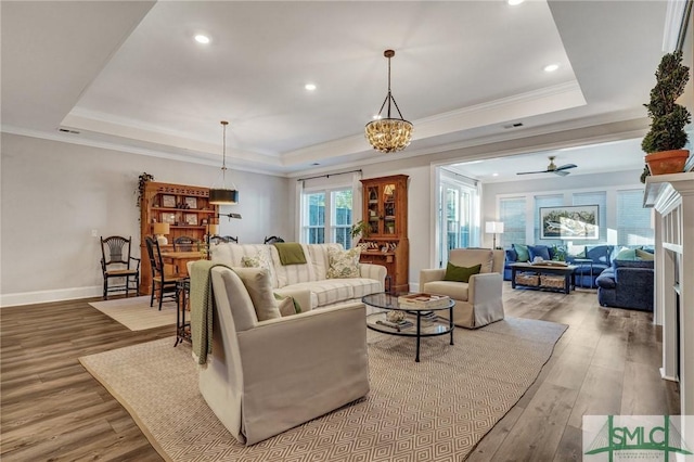 living area featuring recessed lighting, wood finished floors, baseboards, ornamental molding, and a raised ceiling