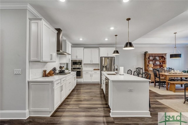 kitchen featuring stainless steel appliances, light countertops, dark wood-type flooring, and wall chimney range hood