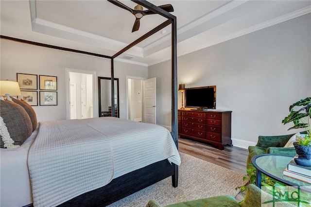 bedroom featuring baseboards, ceiling fan, wood finished floors, a tray ceiling, and crown molding