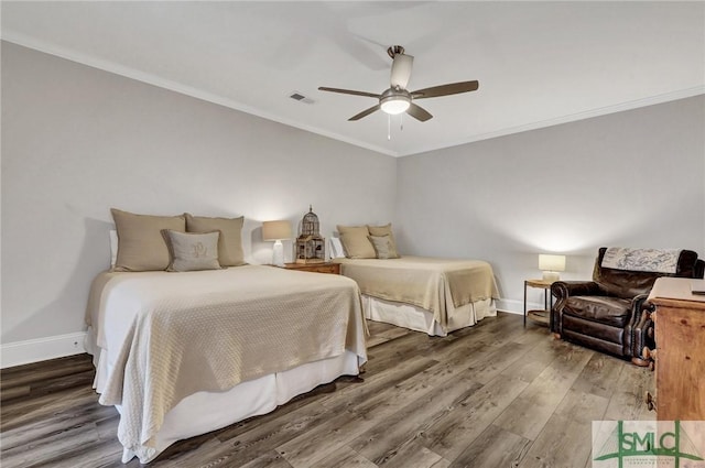 bedroom with baseboards, wood finished floors, visible vents, and crown molding