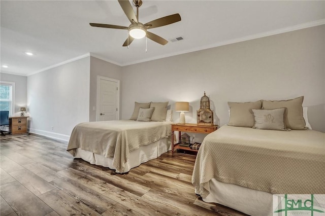 bedroom with baseboards, visible vents, ceiling fan, wood finished floors, and crown molding