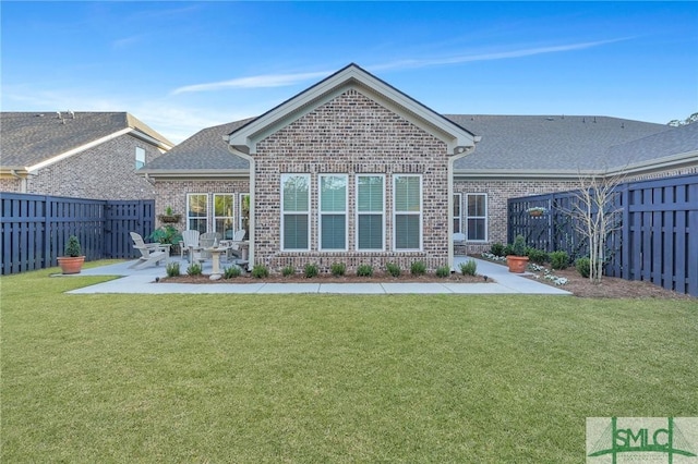 rear view of property with brick siding, a lawn, a fenced backyard, and a patio