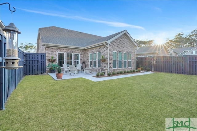 rear view of property with a yard, brick siding, a patio area, and a fenced backyard