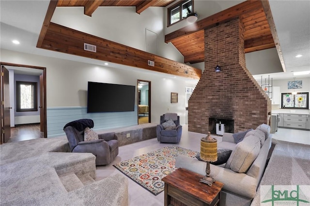 living area featuring visible vents, beamed ceiling, a brick fireplace, and a wealth of natural light