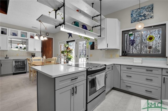 kitchen with beverage cooler, gray cabinetry, open shelves, and stainless steel range with electric cooktop