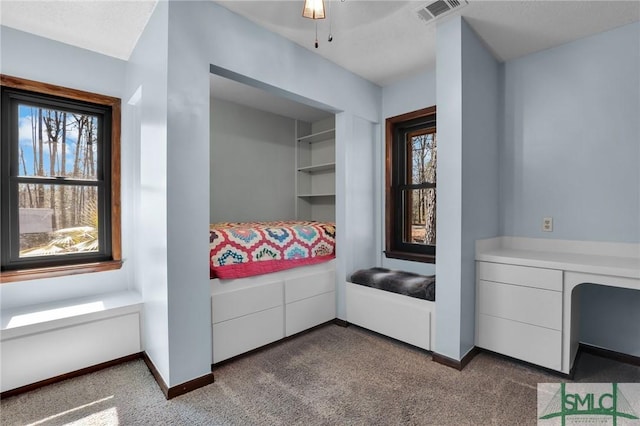 interior space featuring built in desk, multiple windows, visible vents, and baseboards