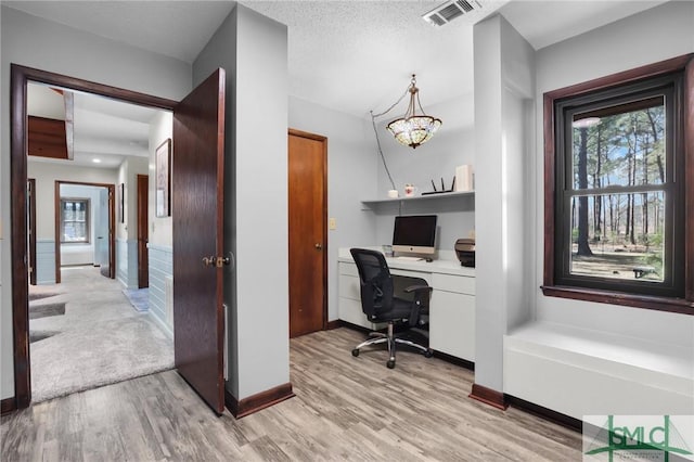 office with a healthy amount of sunlight, light wood-style flooring, and visible vents