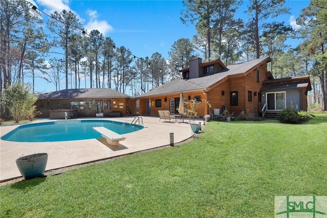 outdoor pool featuring a yard, a patio, a hot tub, and a diving board