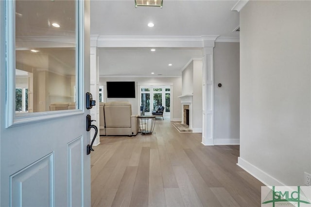 interior space with crown molding, recessed lighting, a fireplace with raised hearth, light wood-style floors, and baseboards