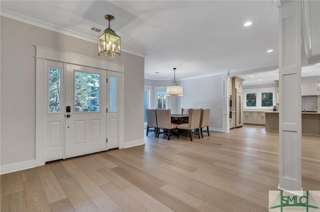 foyer entrance with plenty of natural light, visible vents, crown molding, and light wood-style flooring