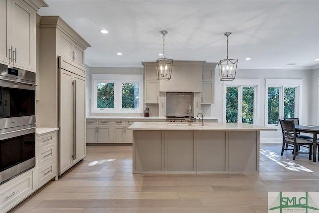 kitchen featuring stainless steel double oven, light countertops, a sink, and paneled refrigerator