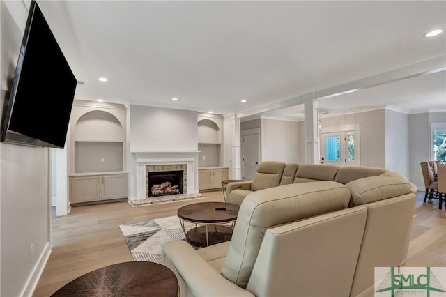 living area with ornamental molding, light wood-type flooring, a brick fireplace, and recessed lighting