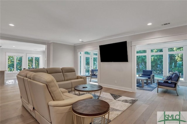 living area featuring light wood-style floors, baseboards, visible vents, and ornamental molding