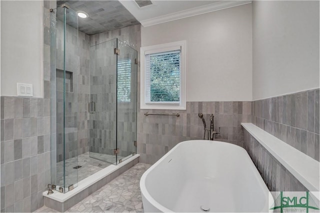 full bath with tile walls, a shower stall, ornamental molding, and a freestanding bath