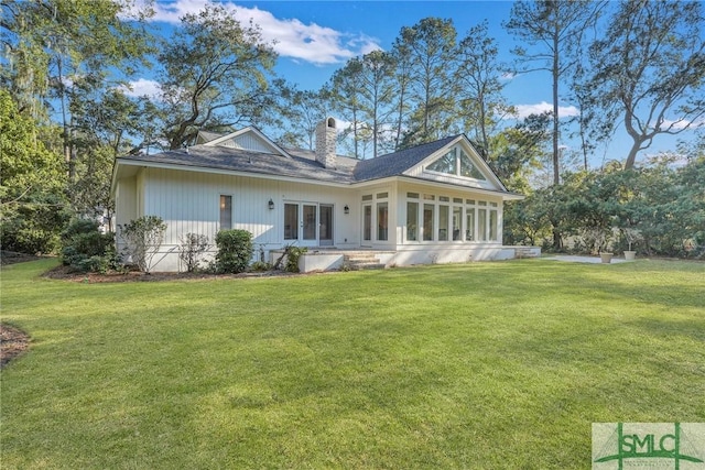 rear view of house featuring a yard, french doors, a chimney, and a sunroom