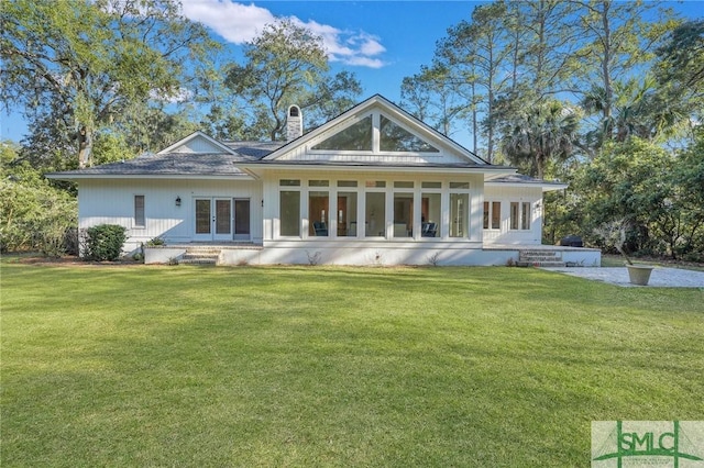 rear view of property with a sunroom, french doors, a yard, and a chimney