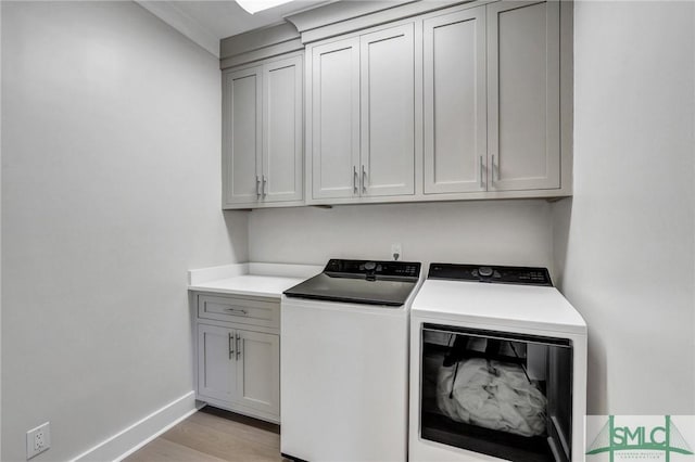 clothes washing area featuring baseboards, separate washer and dryer, cabinet space, and light wood-style floors