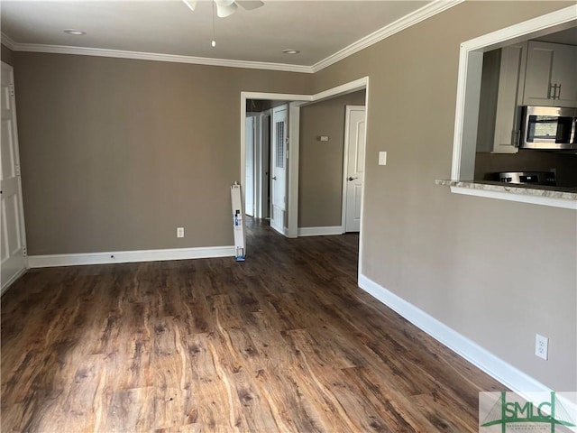 empty room featuring dark wood-style flooring, crown molding, baseboards, and ceiling fan