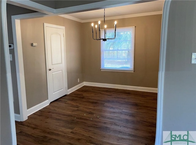 unfurnished dining area featuring dark wood-style flooring, crown molding, baseboards, and an inviting chandelier