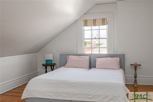 bedroom with baseboards, vaulted ceiling, and wood finished floors