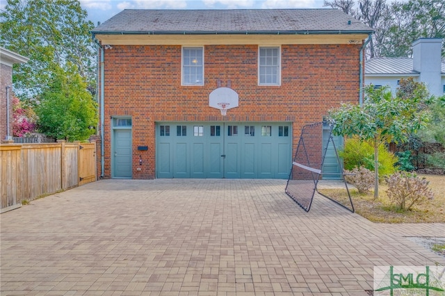 garage featuring decorative driveway and fence