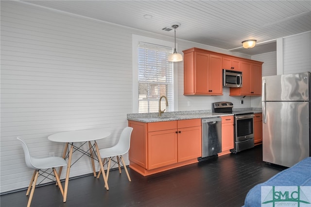 kitchen featuring stainless steel appliances, a sink, visible vents, dark wood finished floors, and decorative light fixtures