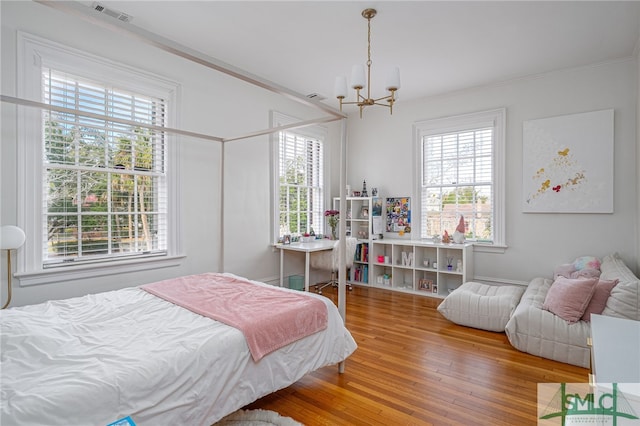 bedroom featuring crown molding, multiple windows, visible vents, and wood finished floors