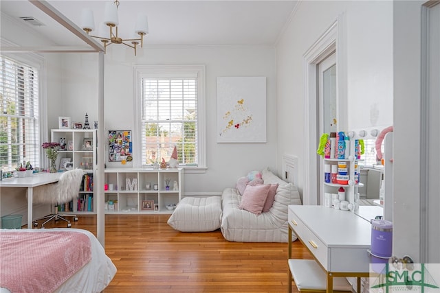 bedroom featuring a notable chandelier, visible vents, hardwood / wood-style floors, and ornamental molding