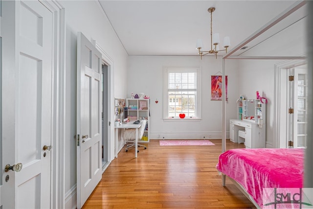 bedroom with light wood-style floors, baseboards, and an inviting chandelier