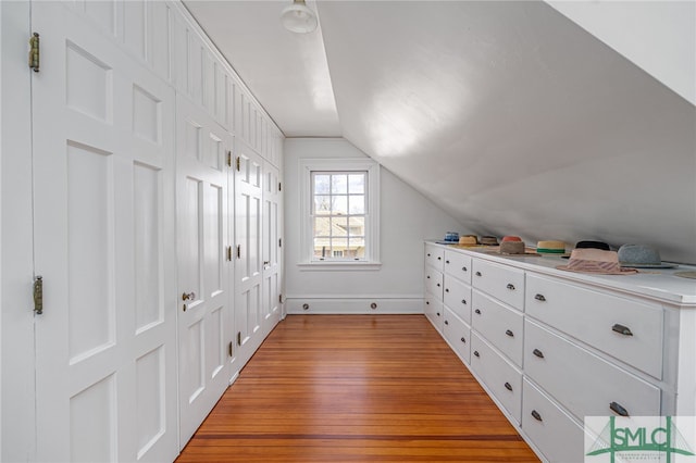 additional living space with lofted ceiling, light wood-type flooring, and baseboards