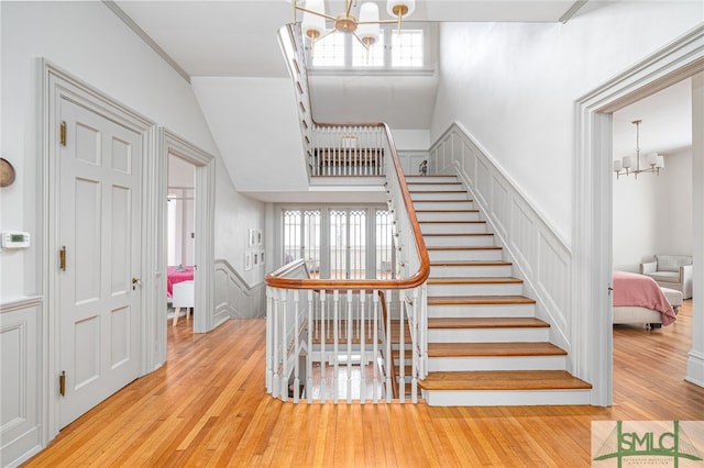 staircase with an inviting chandelier, a decorative wall, and hardwood / wood-style flooring