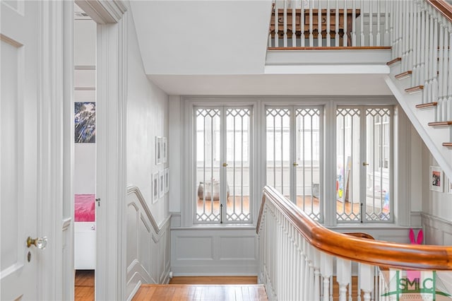 stairway with a wainscoted wall, a decorative wall, and wood finished floors