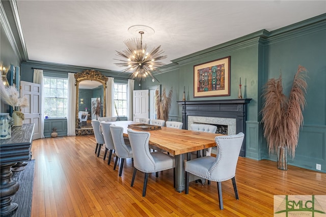 dining room featuring ornamental molding, a chandelier, a decorative wall, and a high end fireplace