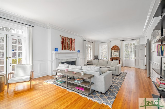 living room featuring a decorative wall, a premium fireplace, ornamental molding, wainscoting, and hardwood / wood-style floors