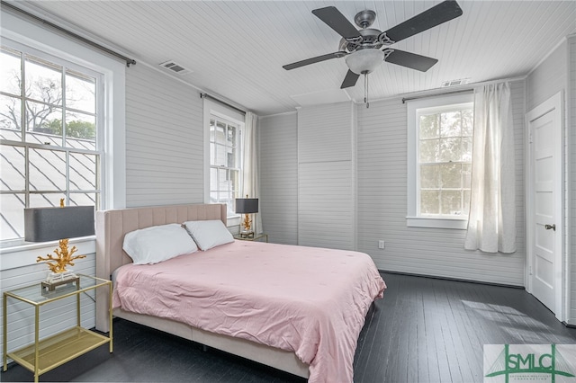 bedroom with wood-type flooring, visible vents, and multiple windows