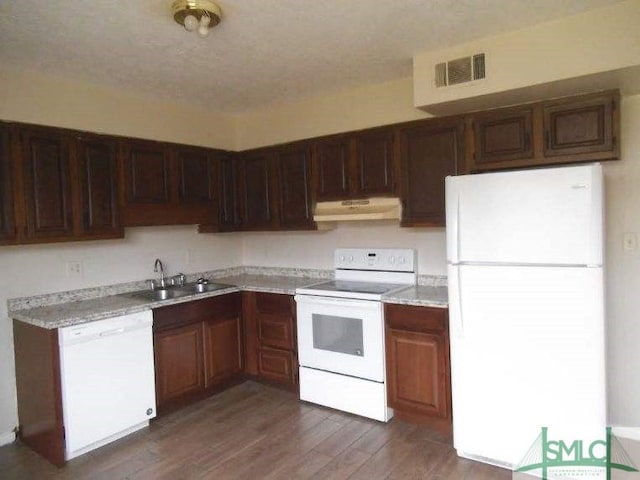 kitchen featuring white appliances, visible vents, light countertops, under cabinet range hood, and a sink